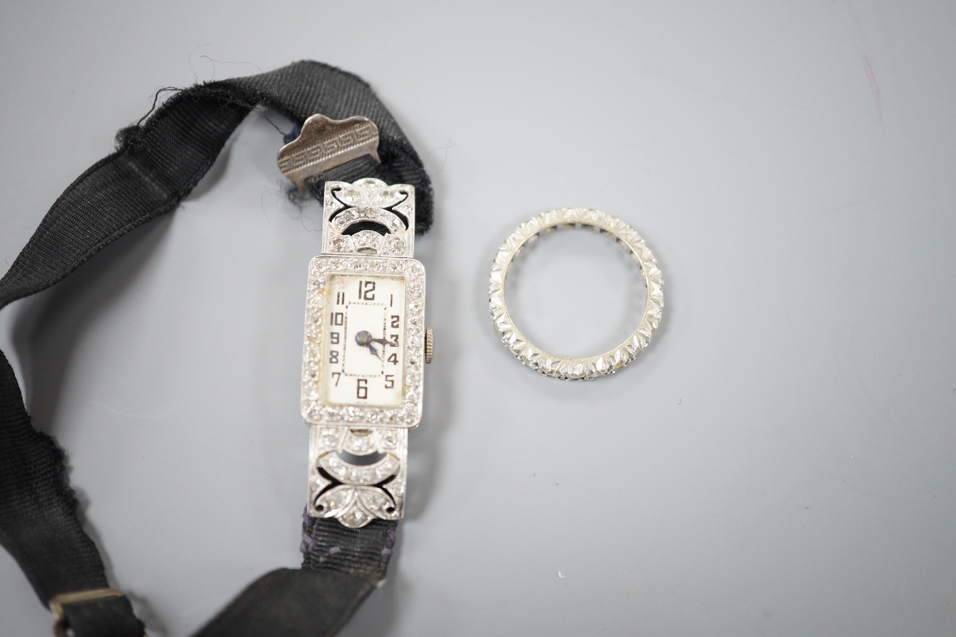 A lady's white metal (stamped all platinum) and diamond set manual wind cocktail watch, gross weight 13.2 grams and a 9ct white metal and synthetic white spinel set full eternity ring.